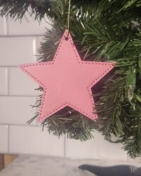 Pink leatherette star ornament with stitched border hanging on Christmas tree branch